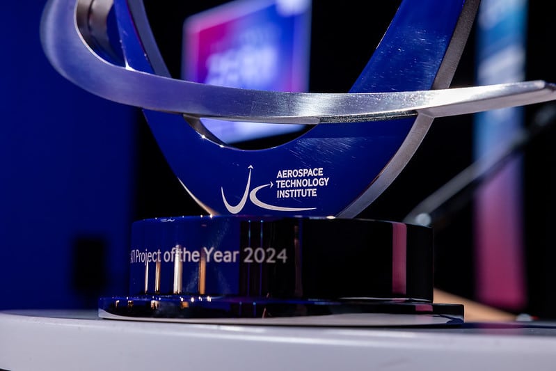 Close-up of the Aerospace Technology Institute’s Project of the Year 2024 trophy, displayed on a stage with blurred background screens.