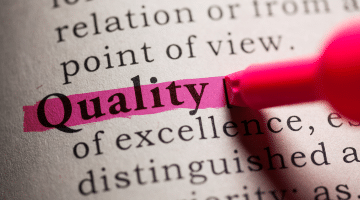 The word “Quality” highlighted in pink on a dictionary page using a pink highlighter pen.