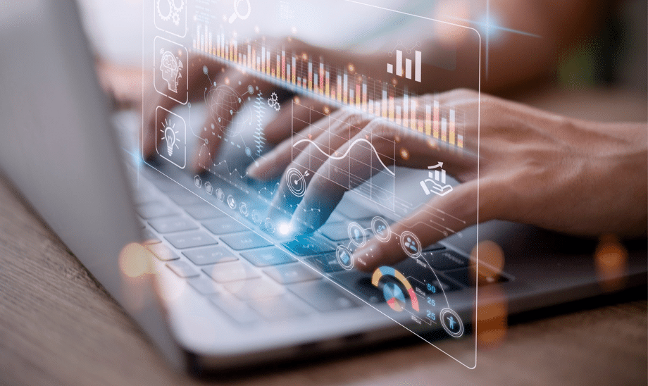 Close-up of hands typing on a laptop with futuristic digital overlay showing data analytics, charts, and AI icons, symbolising innovation, automation, and digital transformation.
