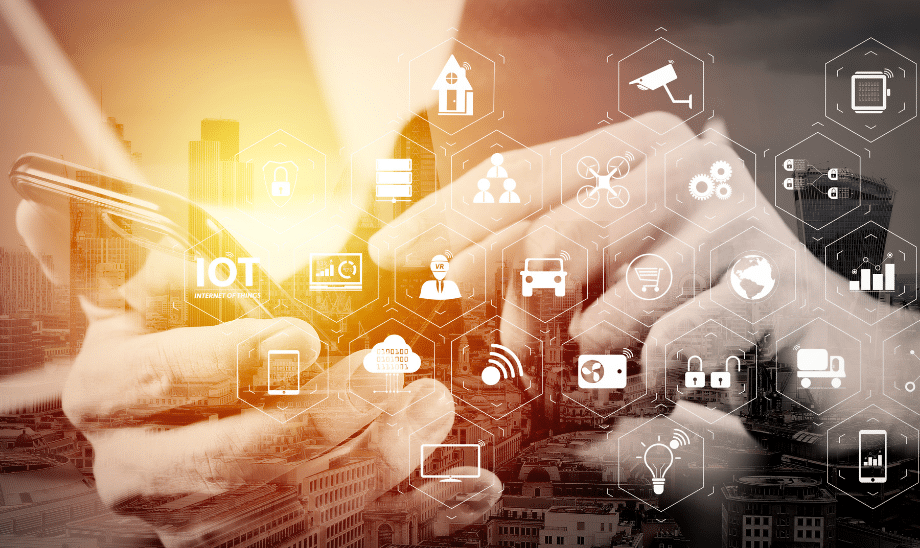 Close-up of hands using a smartphone with Internet of Things (IoT) icons overlayed, representing smart devices, connectivity, and data integration in a cityscape